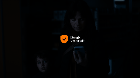 Vrouw met kind aan de hand kijkt op telefoon in donkere winkel (tekst op de foto: Denk Vooruit)