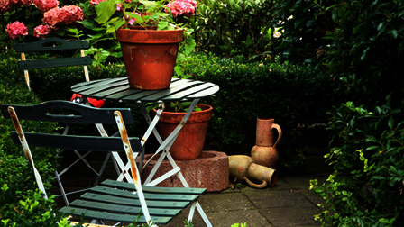 2 stoelen en een tafel in een groene tuin.